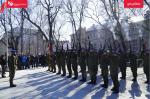Na placu stoją żołnierze w dwuszeregu i oddają salwę honorową.