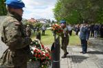 Żołnierz składa kwiaty pod pomnikiem. 