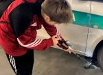 Chłopiec sprawdza podwozie samochodu lusterkiem 